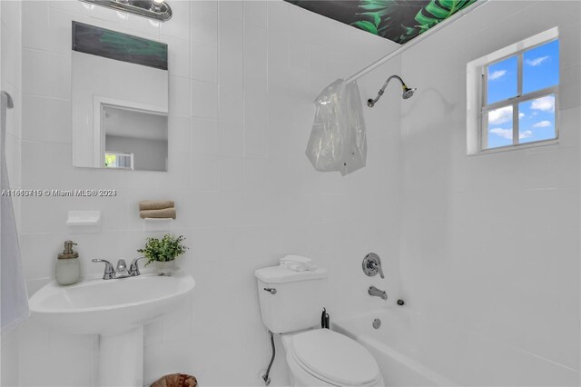 bathroom featuring tile walls, toilet, and shower / tub combo