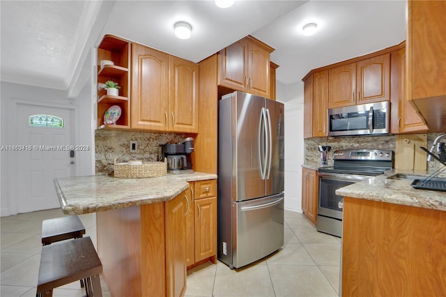 kitchen featuring kitchen peninsula, tasteful backsplash, a kitchen bar, appliances with stainless steel finishes, and sink