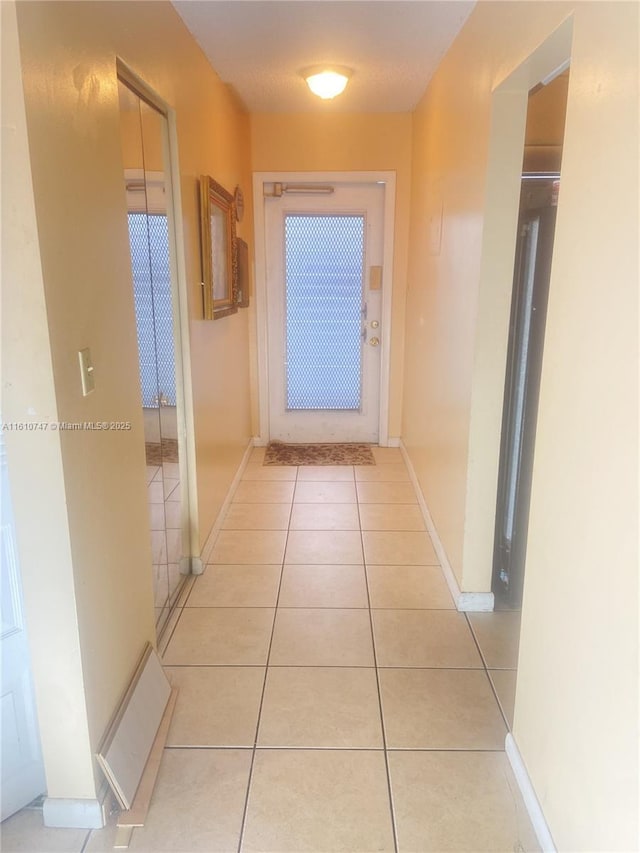 hallway featuring baseboards and light tile patterned floors