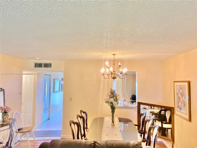 dining room with a chandelier, visible vents, and a textured ceiling