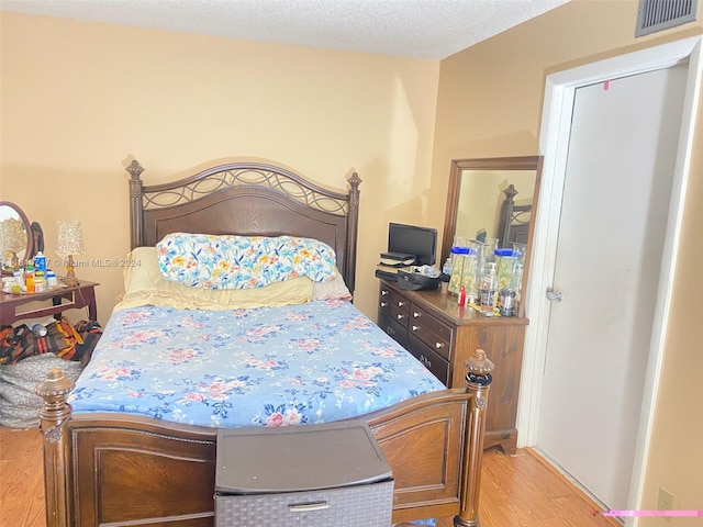 bedroom with a textured ceiling and light hardwood / wood-style floors