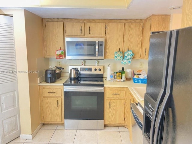 kitchen featuring light tile patterned floors, stainless steel appliances, light brown cabinetry, and sink