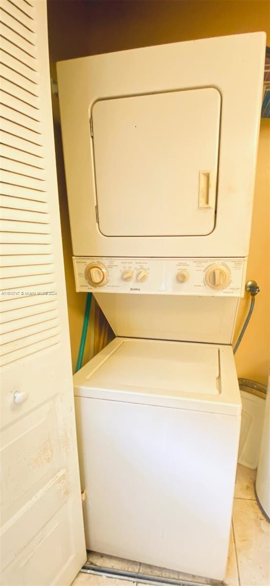 laundry area featuring light tile patterned floors and stacked washer / drying machine