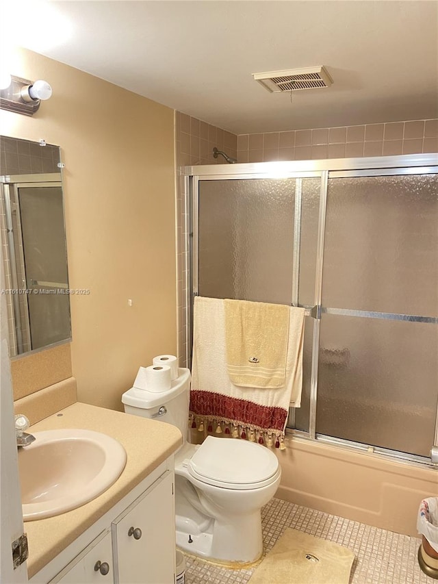 bathroom featuring shower / bath combination with glass door, visible vents, toilet, vanity, and tile patterned floors