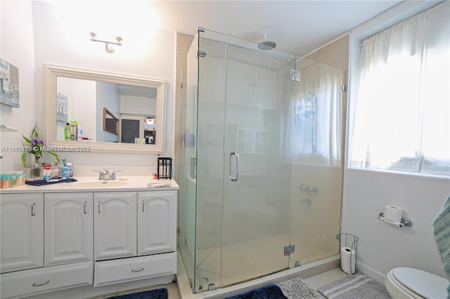 bathroom with a shower with door, vanity, a healthy amount of sunlight, and toilet