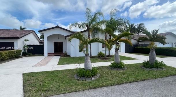 view of front of house featuring driveway, a front lawn, and stucco siding