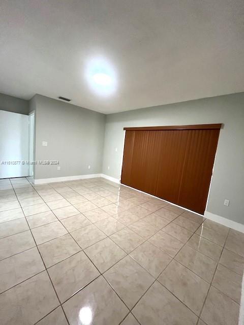 spare room featuring light tile patterned floors, visible vents, and baseboards