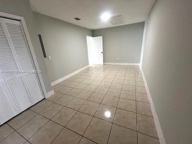 unfurnished bedroom with a closet, light tile patterned flooring, visible vents, and baseboards