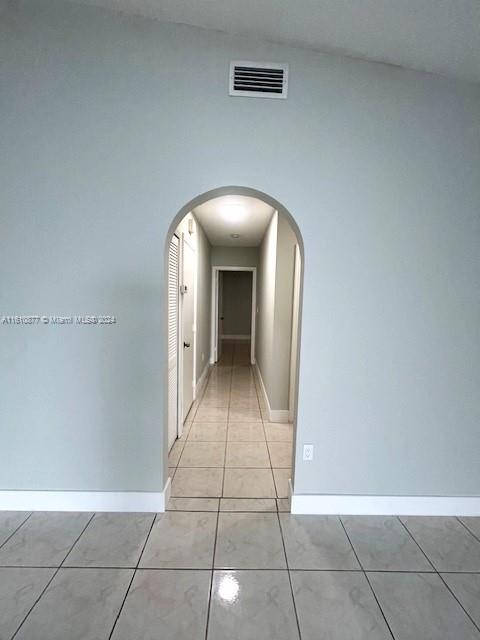 hall with vaulted ceiling and light tile floors