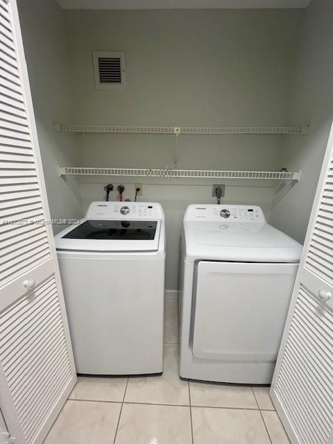 laundry area featuring laundry area, visible vents, washer and clothes dryer, and light tile patterned floors