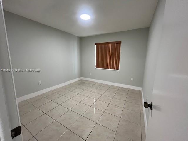 spare room featuring baseboards and light tile patterned floors