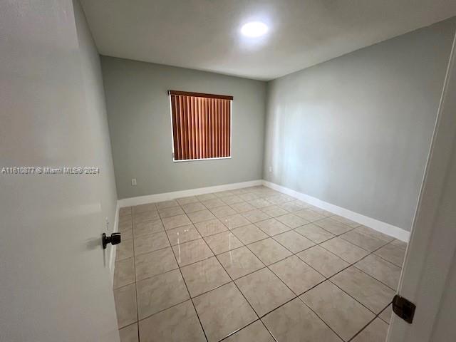 empty room with light tile patterned flooring and baseboards