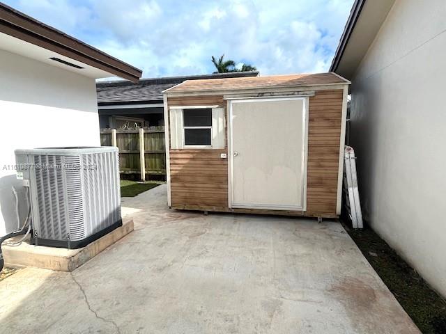 view of outdoor structure featuring fence, cooling unit, and an outbuilding