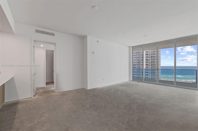 spare room with floor to ceiling windows and a water view