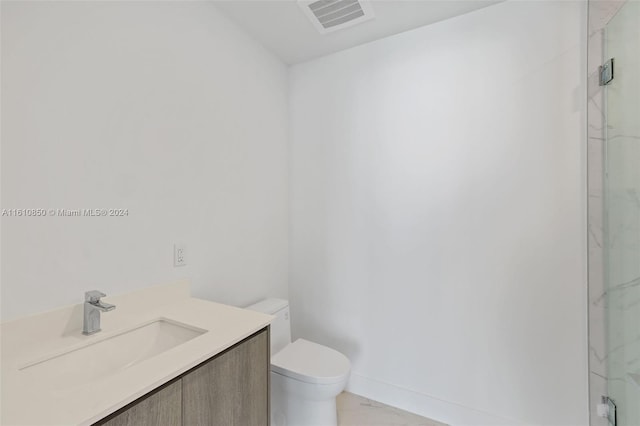 bathroom with vanity, a shower with shower door, and toilet