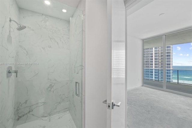 bathroom with a shower with door, a wall of windows, and a water view