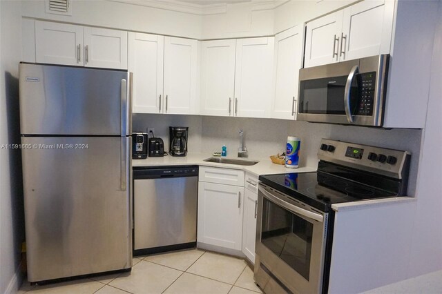 kitchen featuring light tile patterned floors, a sink, white cabinetry, light countertops, and appliances with stainless steel finishes
