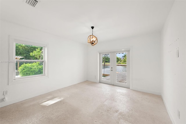 unfurnished room featuring french doors and a chandelier