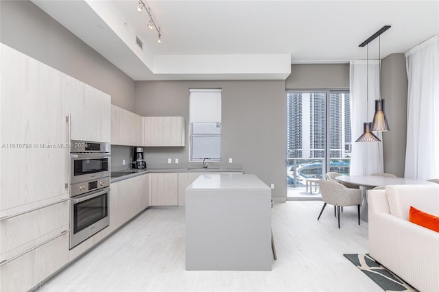 kitchen featuring decorative light fixtures, a kitchen island, rail lighting, sink, and stainless steel double oven