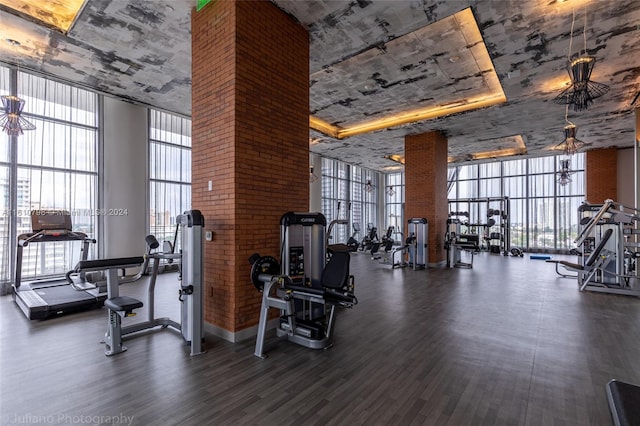 exercise room featuring dark hardwood / wood-style floors, brick wall, and expansive windows