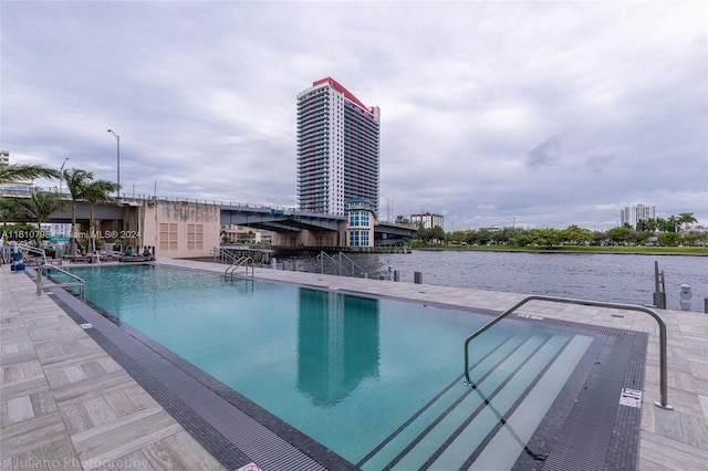 view of pool with a water view and a patio