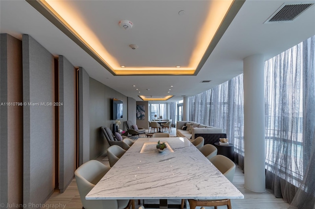 dining room featuring light hardwood / wood-style flooring and a raised ceiling