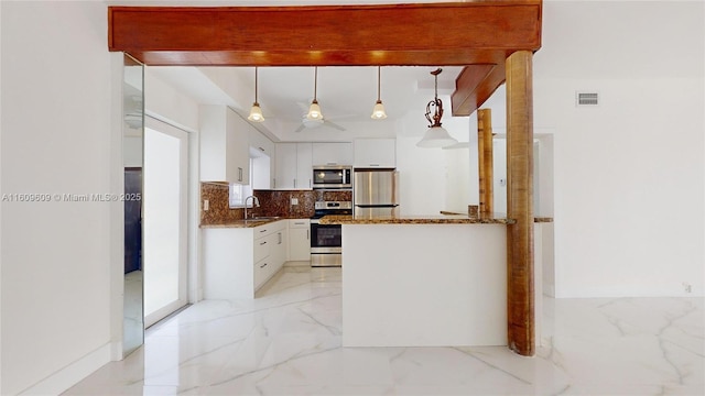 kitchen featuring appliances with stainless steel finishes, white cabinetry, hanging light fixtures, kitchen peninsula, and backsplash