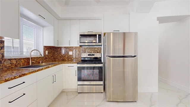 kitchen featuring white cabinets, appliances with stainless steel finishes, dark stone counters, sink, and backsplash