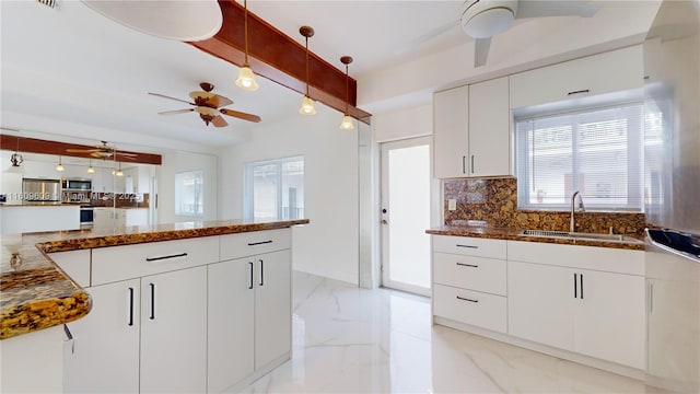 kitchen with sink, white cabinetry, pendant lighting, and tasteful backsplash