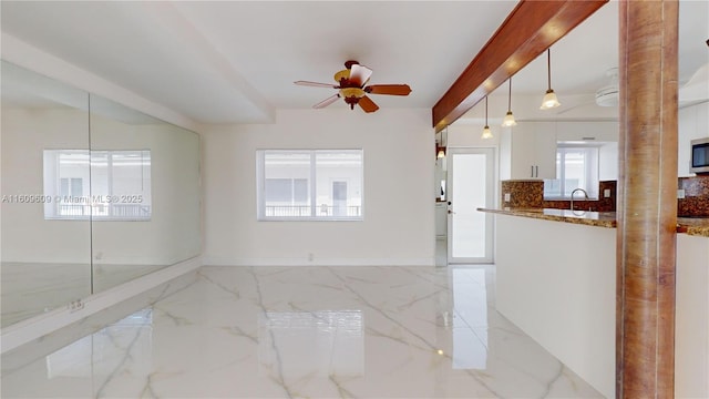 empty room with beam ceiling and ceiling fan