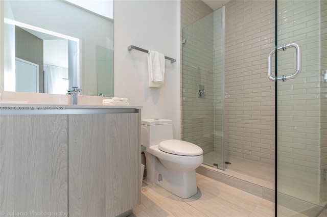 bathroom featuring a shower with door, tile flooring, toilet, and vanity