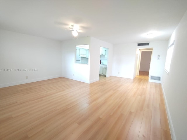 spare room with a ceiling fan, light wood-style floors, visible vents, and baseboards