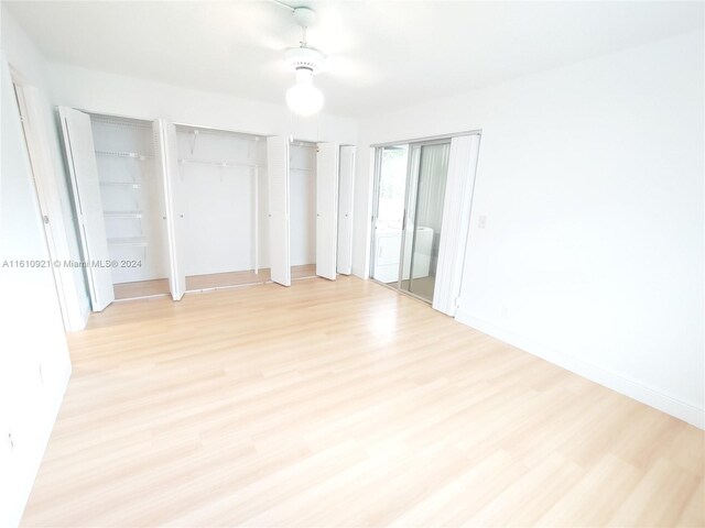 unfurnished bedroom with multiple closets, ceiling fan, and light wood-type flooring