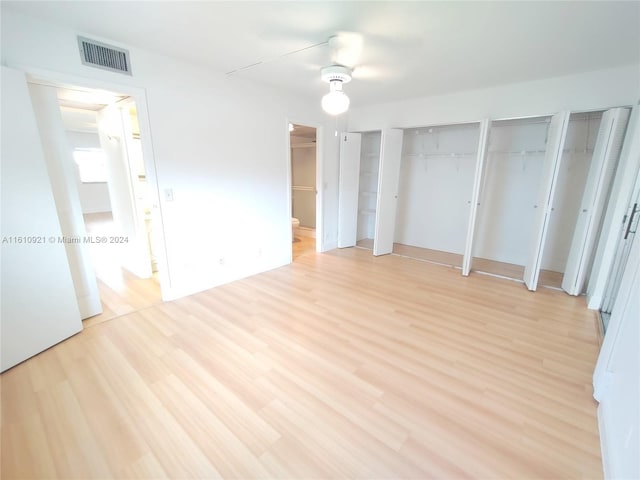 unfurnished bedroom featuring multiple closets, ceiling fan, and light hardwood / wood-style flooring