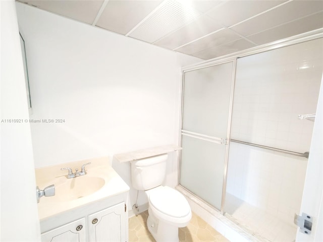 bathroom with a shower with shower door, vanity, tile patterned flooring, and toilet