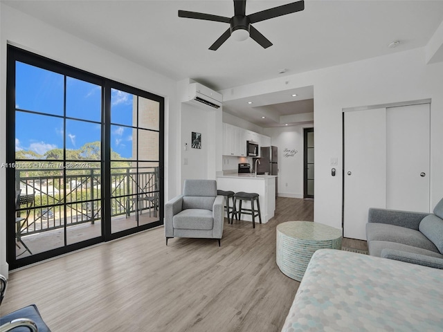 living room featuring baseboards, a wall unit AC, ceiling fan, light wood-type flooring, and recessed lighting