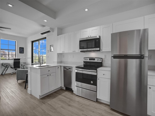 kitchen with a peninsula, a sink, open floor plan, appliances with stainless steel finishes, and a wall mounted AC