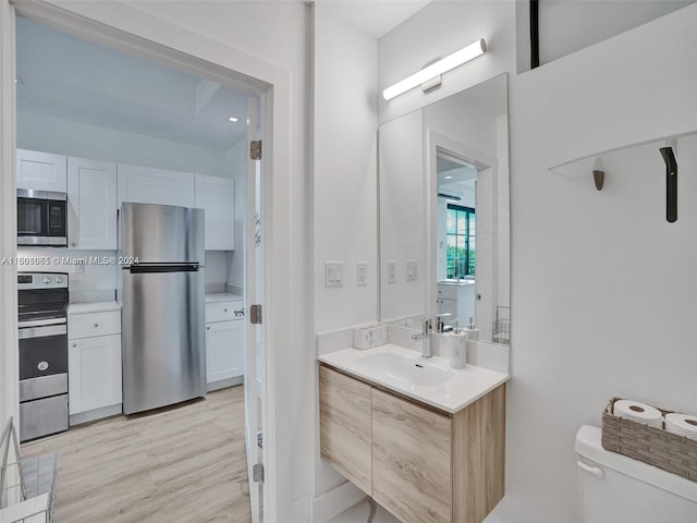 bathroom featuring toilet, wood finished floors, and vanity