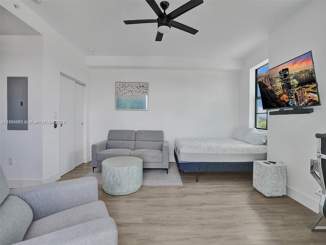 bedroom featuring a ceiling fan, electric panel, baseboards, and wood finished floors