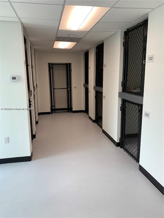 empty room featuring baseboards, a paneled ceiling, and finished concrete floors