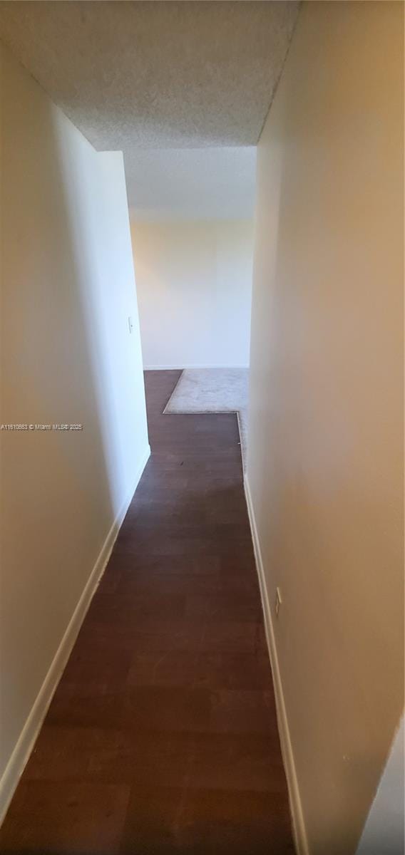 corridor with dark wood-type flooring and a textured ceiling