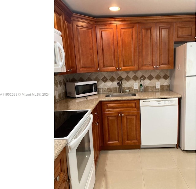 kitchen with white appliances, sink, backsplash, and light stone counters