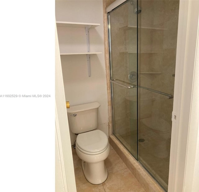 bathroom featuring walk in shower, tile patterned floors, and toilet