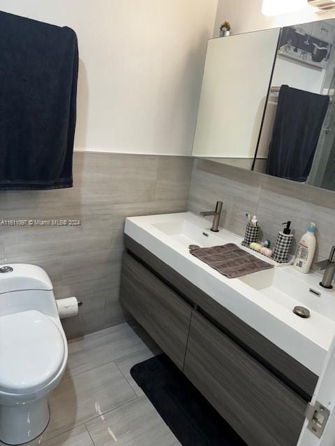 bathroom with tasteful backsplash, tile walls, tile floors, toilet, and vanity