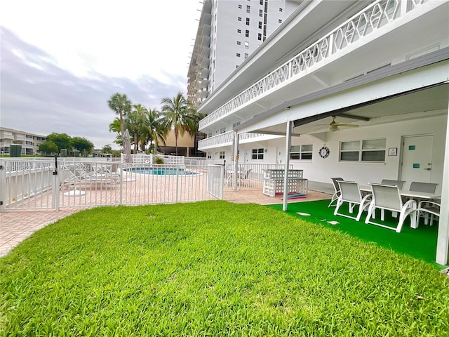 view of yard with a patio, ceiling fan, and a fenced in pool