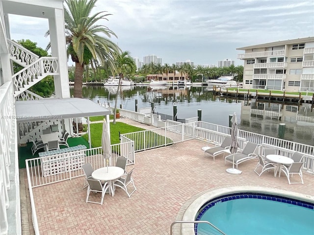 view of pool featuring a boat dock, a water view, and a patio area