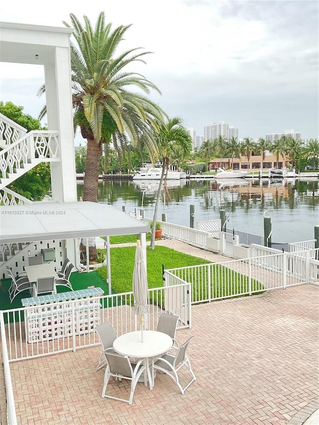 view of patio with a water view and a dock