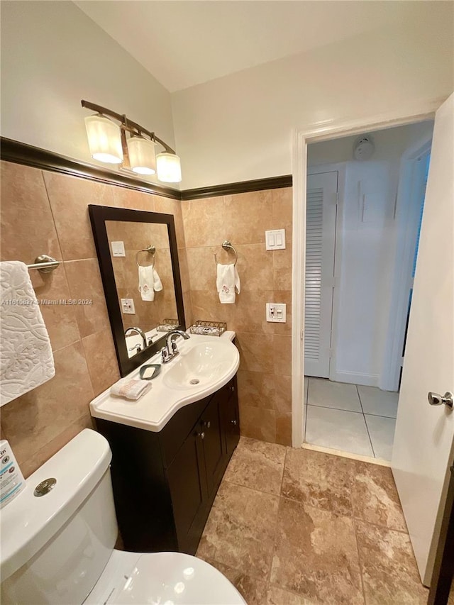 bathroom with tile walls, vanity, and toilet