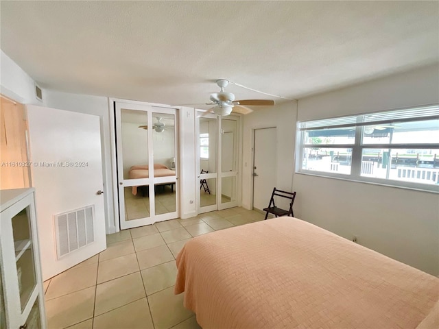 bedroom featuring ceiling fan, light tile patterned flooring, french doors, and a textured ceiling