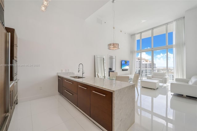 kitchen featuring decorative light fixtures, sink, light tile patterned flooring, light stone counters, and expansive windows